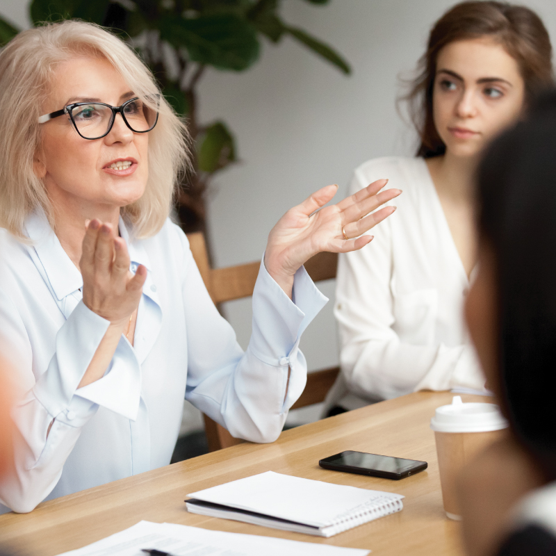 Female business leader talking at conference room meeting with coworkers
