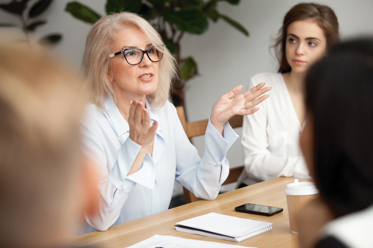 Female business leader talking at conference room meeting with coworkers