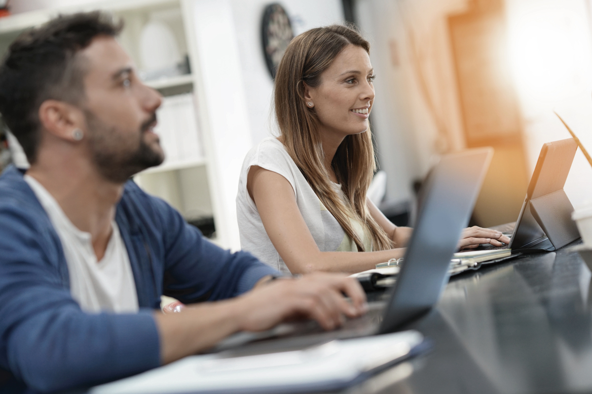 Man and woman working on laptops in office