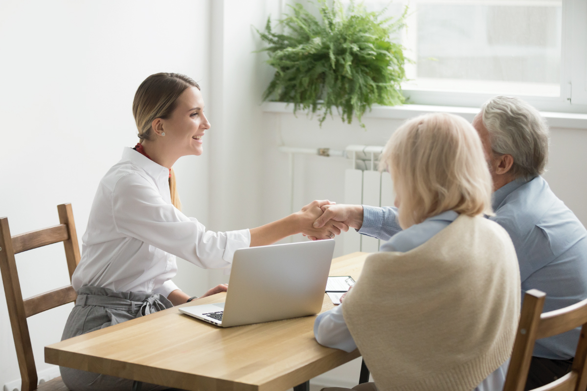 Female business leader shaking hands with senior couple